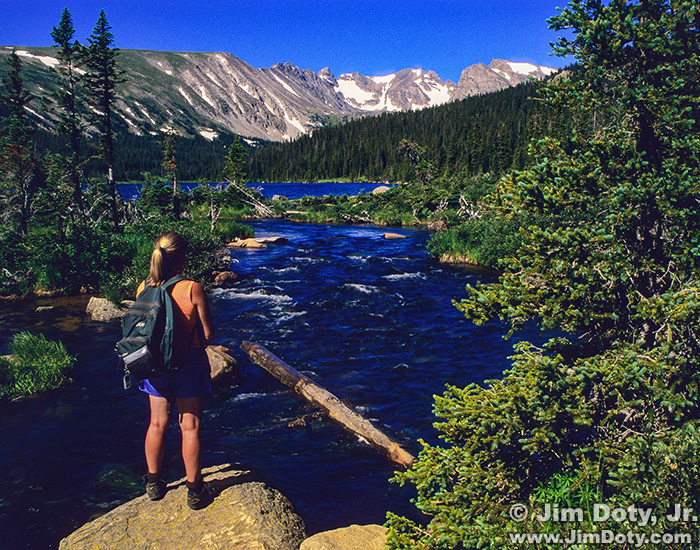 Hiker at the steam flowing out of Long Lake. Indian Peaks Wilderness, Colorado.