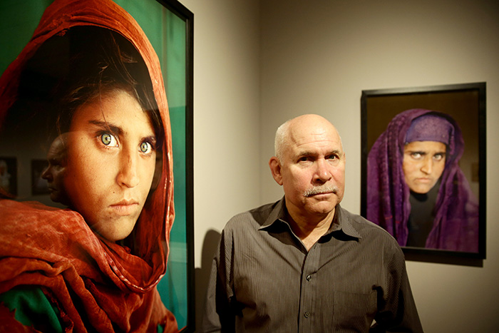 Photographer Steve McCurry next to his images of Sharbat Gula, "Afghan Girl".